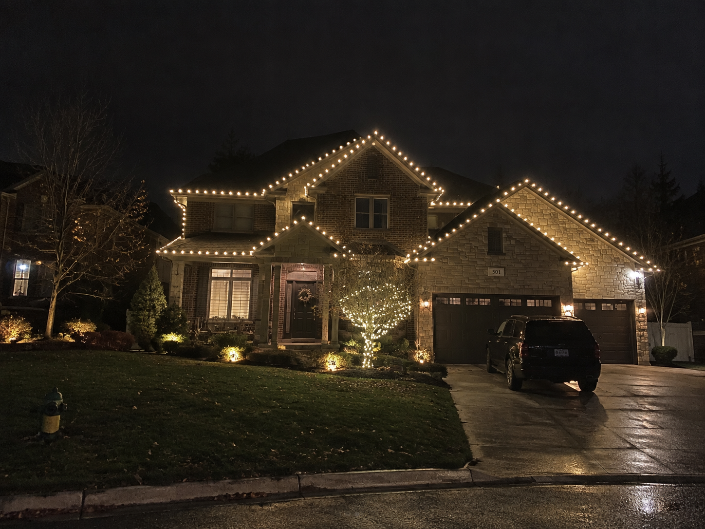 Warm white roofline lights on a brick and stone home